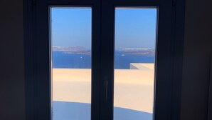 Une pièce dotée d’une grande fenêtre donnant sur une plage et la mer.