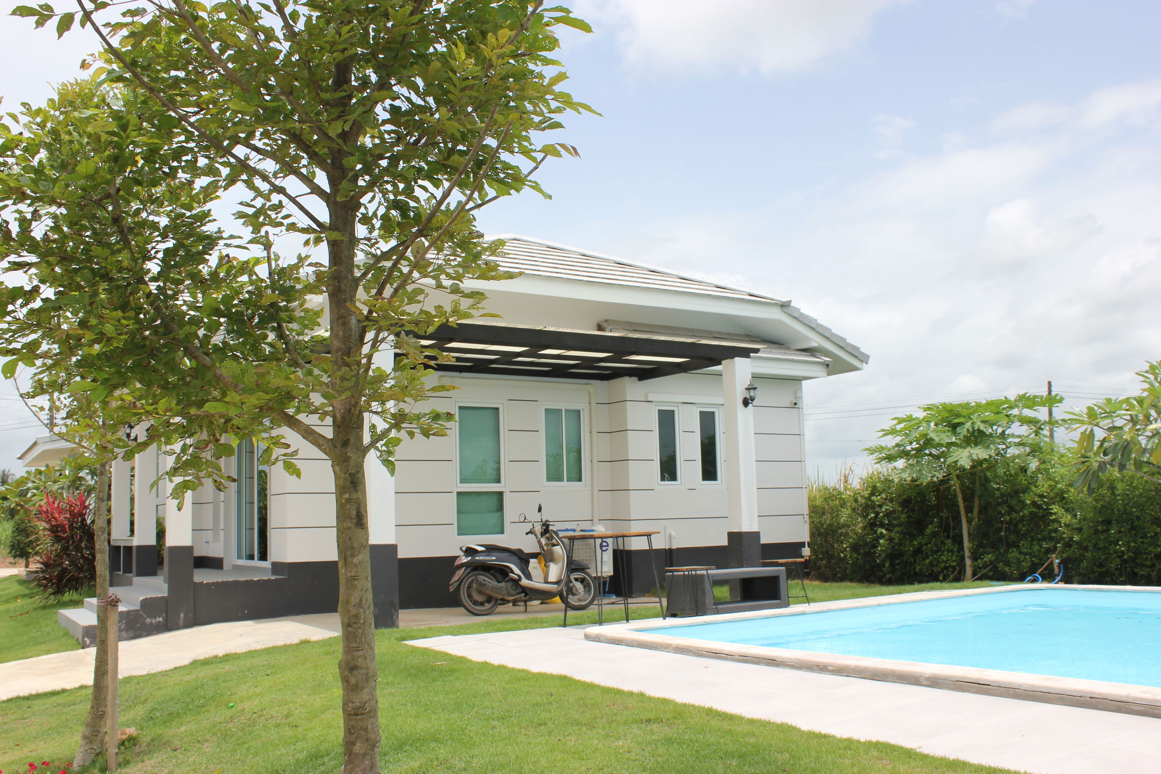 A house with a covered patio, a swimming pool, and a scooter parked outside.