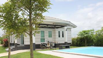 A house with a covered patio, a swimming pool, and a scooter parked outside.