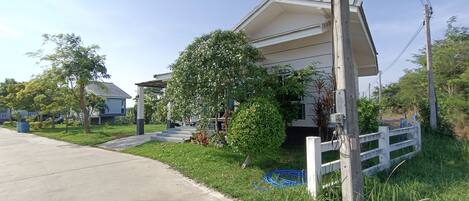 A residential house with a covered porch, a small front yard, and a wooden fence.