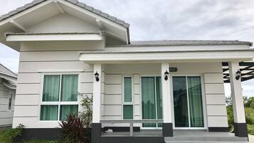 A modern two-story house with a covered porch, large windows, and a well-maintained lawn.