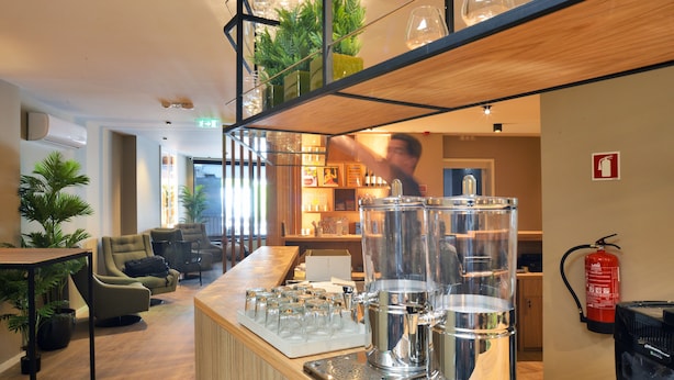 A bar area with a barista preparing drinks, a fire extinguisher, and seating with a view of the bar. - Spot Apartments Trindade (Porto)