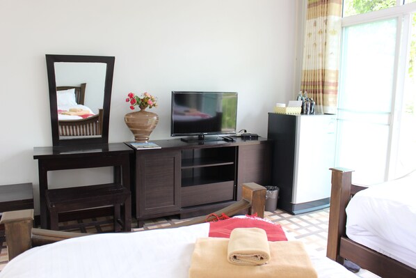 A hotel room with a bed, a TV, a mirror, a desk, and a window with curtains.