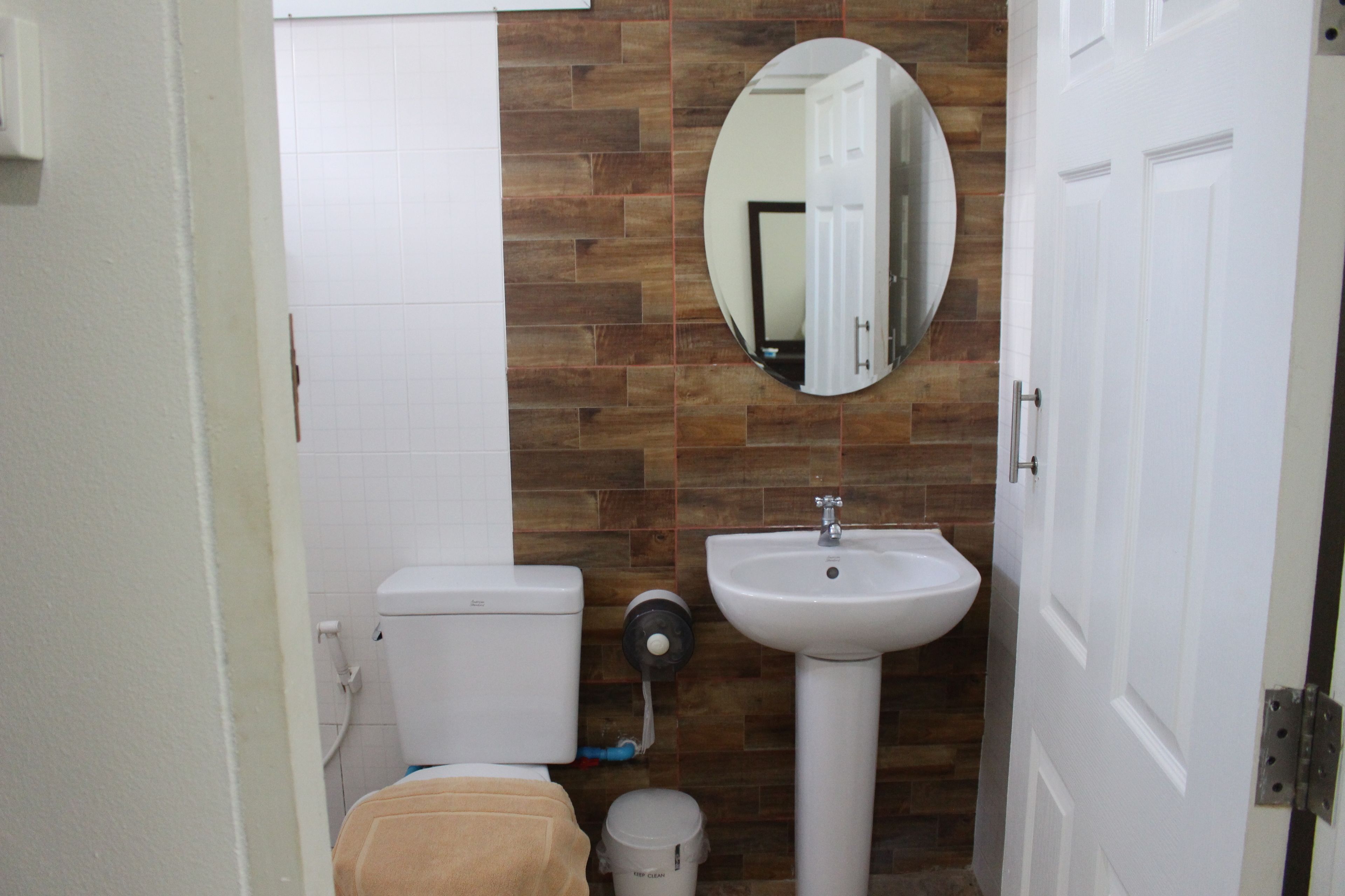 A bathroom with a toilet, sink, and mirror.