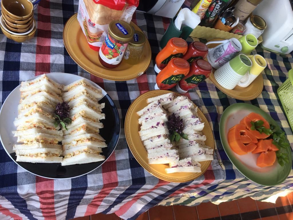 A table with sandwiches, condiments, and a checkered tablecloth.