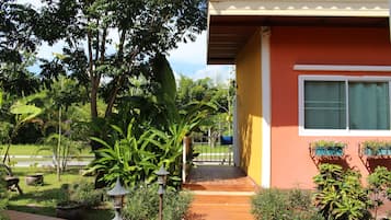 Una casa con terraza de madera, un jardín con diversas plantas y un buzón.