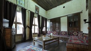 A room with a wooden sofa, a coffee table, a patterned rug, and a wooden cabinet. - Ali Bey Konagi (Gaziantep)