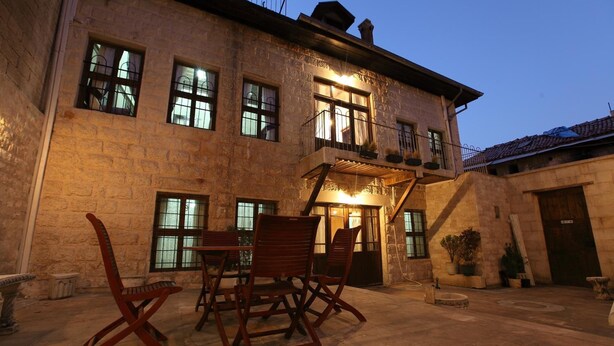 A stone building with a balcony, outdoor seating, and a large window. - Ali Bey Konagi (Gaziantep)