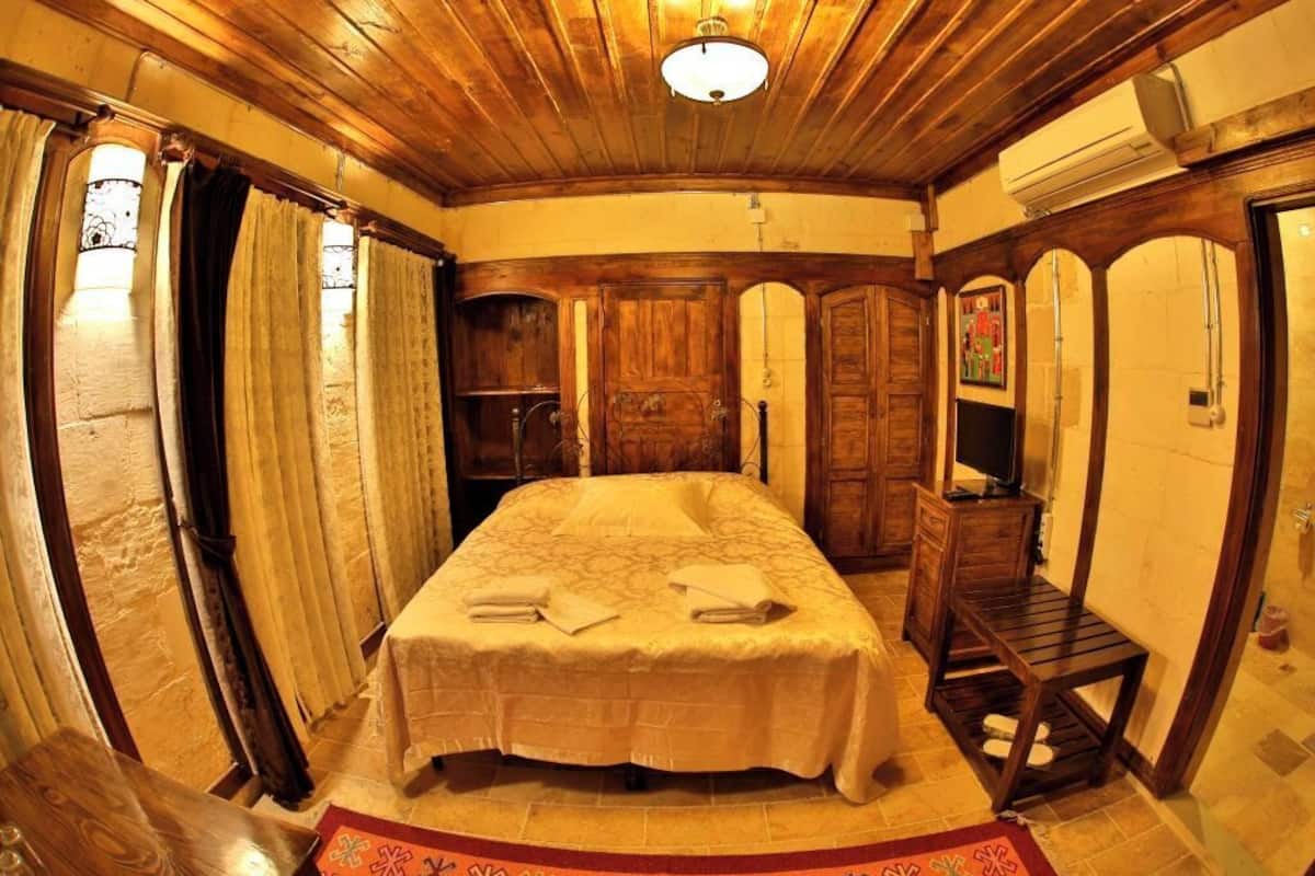 Ein Zimmer mit einem Bett, Holzmöbeln und einem Fernseher.