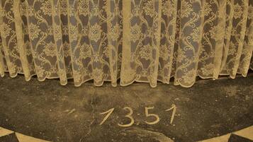 A patterned curtain with a number "7351" on a textured floor.