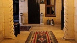 A hallway with a patterned rug, wooden ceiling beams, and a hanging light fixture. - Ali Bey Konagi (Gaziantep)