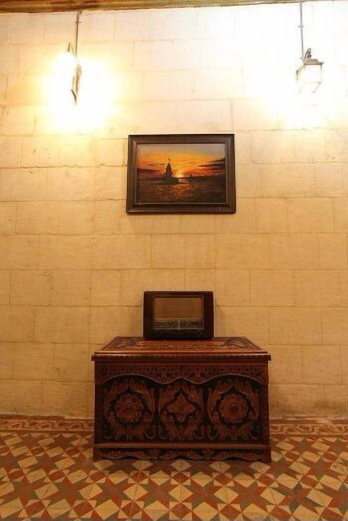Una habitación con piso estampado, un cuadro en la pared y un armario de madera.