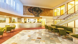 Un vestíbulo de hotel con mostrador de recepción, zona de estar y una escalera.