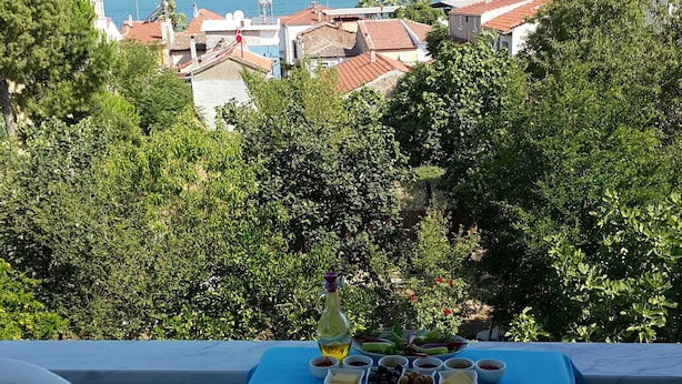 Mesa de comedor al aire libre con diferentes platos y vista a un pueblo costero.