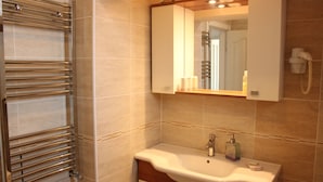 Un baño con toallero, lavamanos, espejo y teléfono.