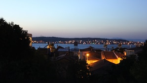 Un pueblo costero al atardecer, con edificios visibles y una extensión de agua.