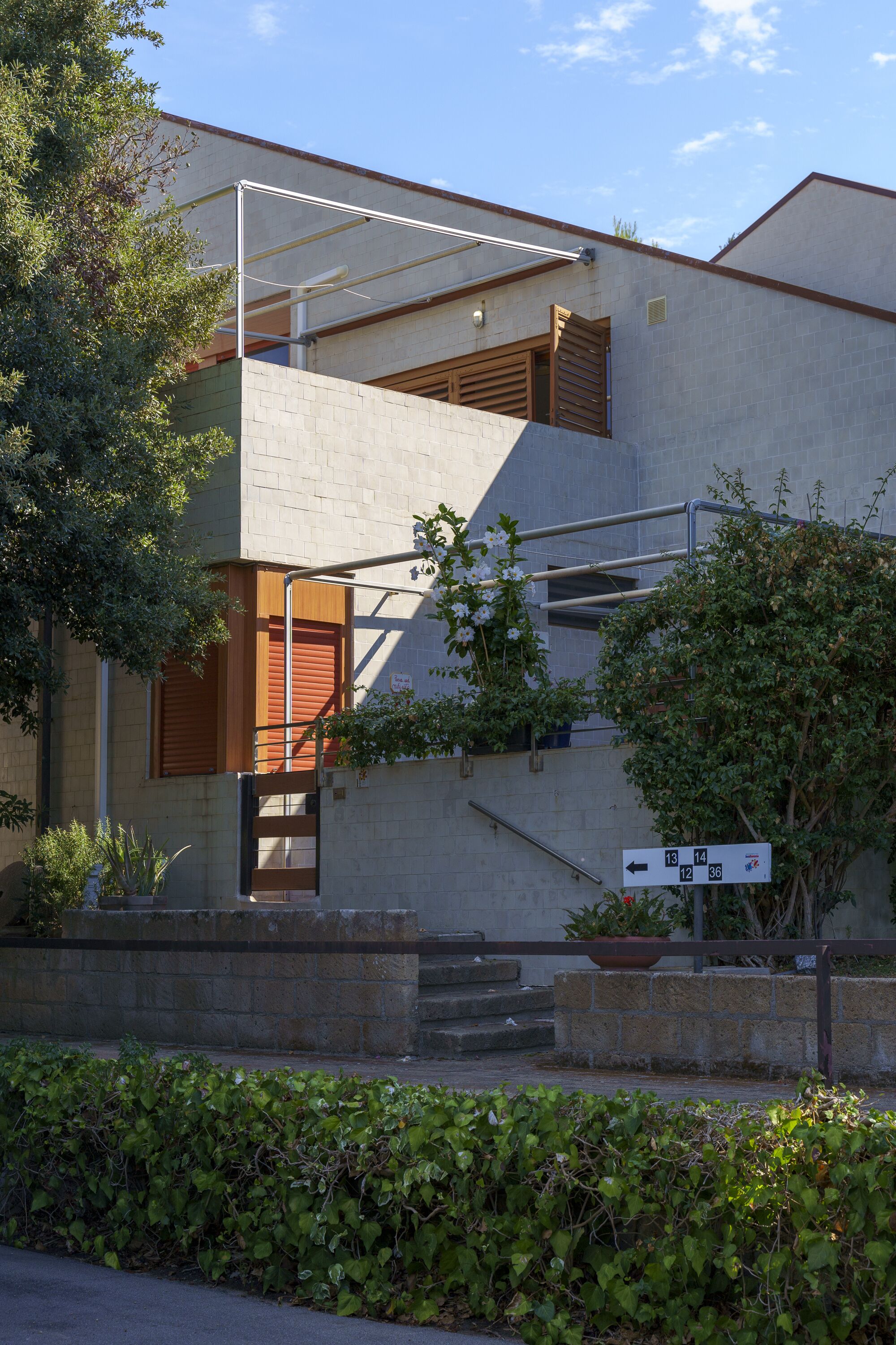 A modern two-story building with a concrete facade, a wooden door, and a staircase leading to the upper level.