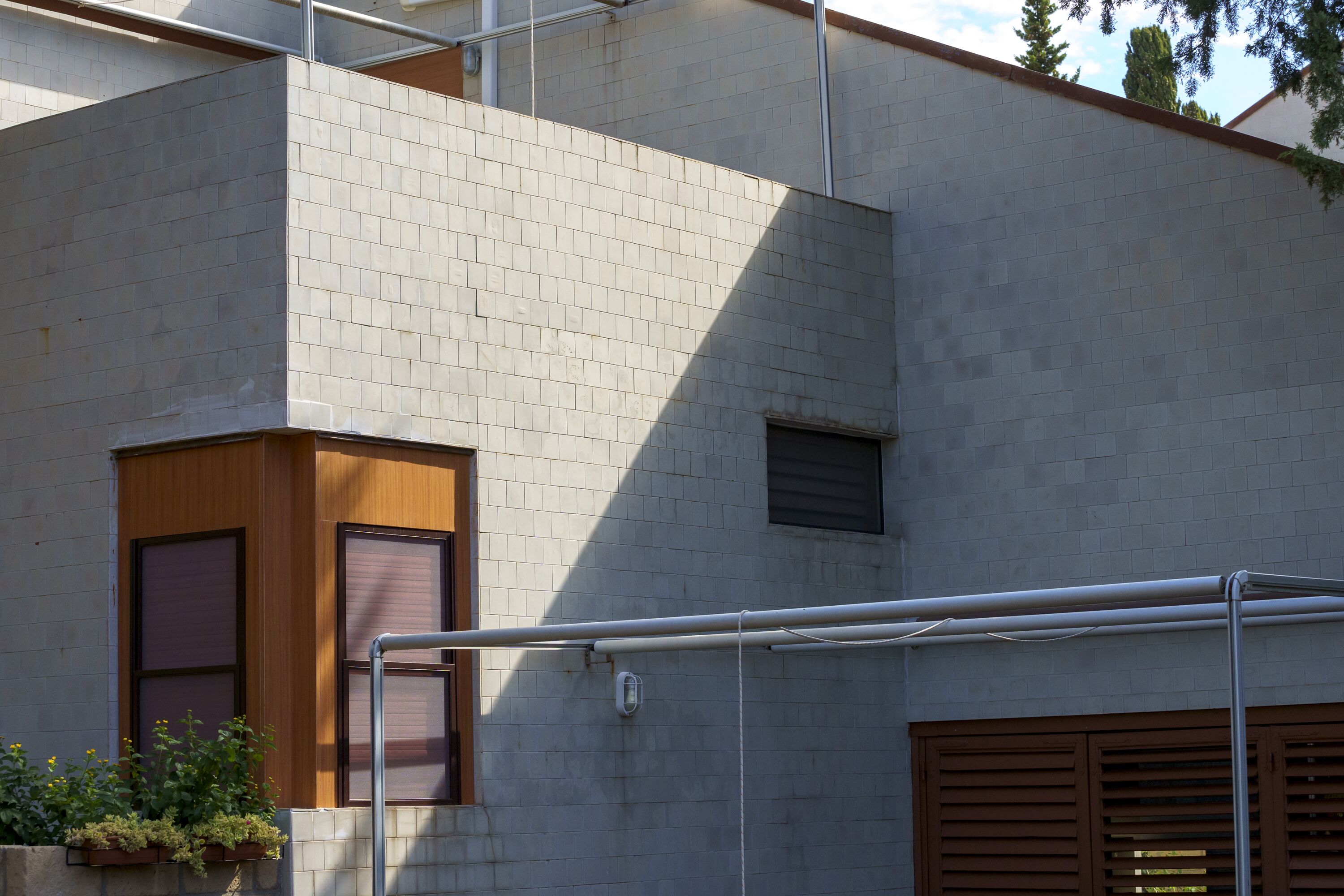 Un edificio moderno con fachada de tejas grises, una puerta de madera y una ventana con persianas.