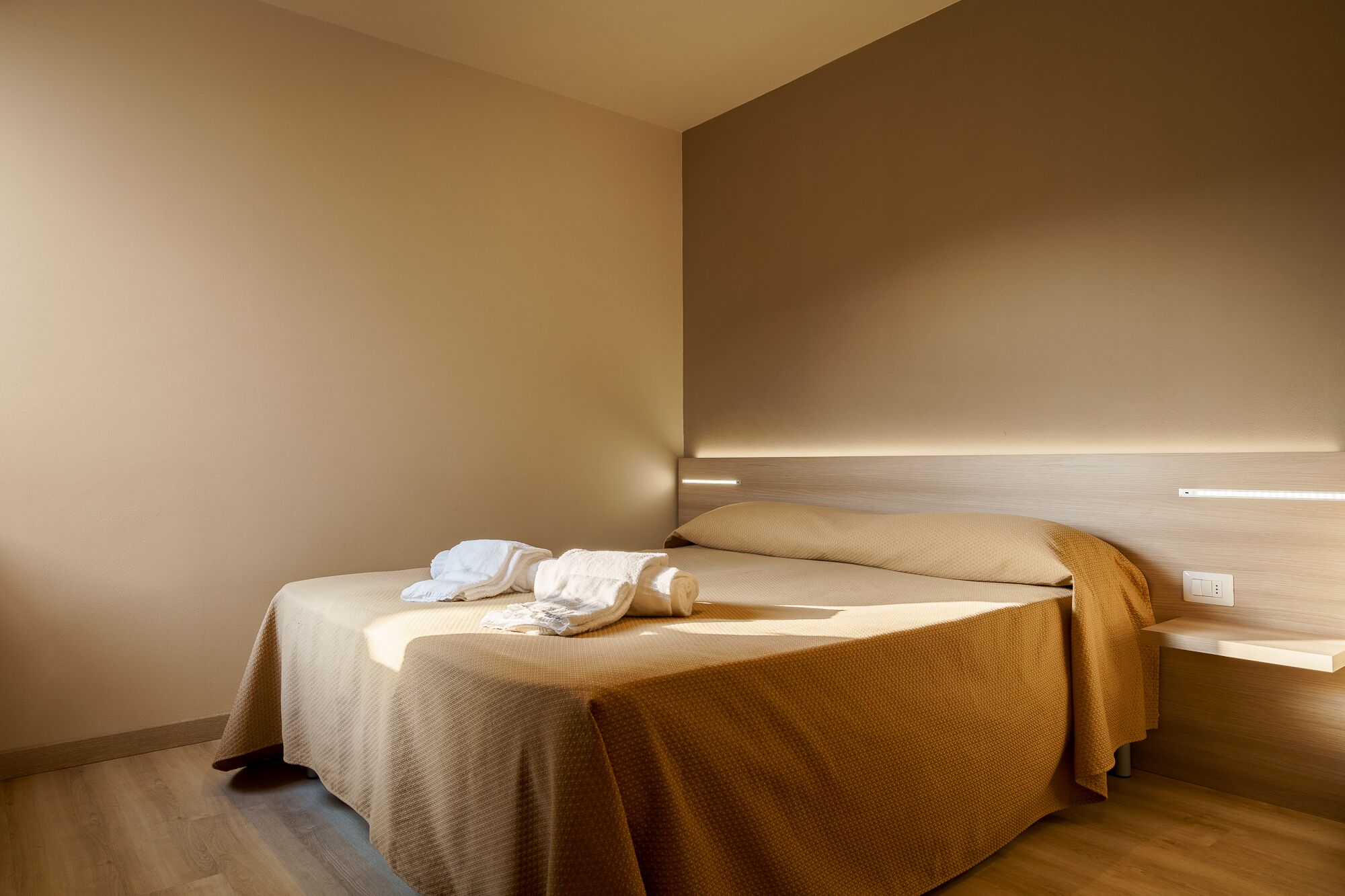 Ein modernes Hotelzimmer mit einem Bett, einem Nachttisch und einer Wandleuchte.