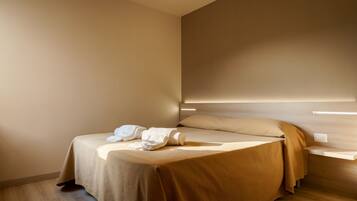 Ein modernes Hotelzimmer mit einem Bett, einem Nachttisch und einer Wandleuchte.