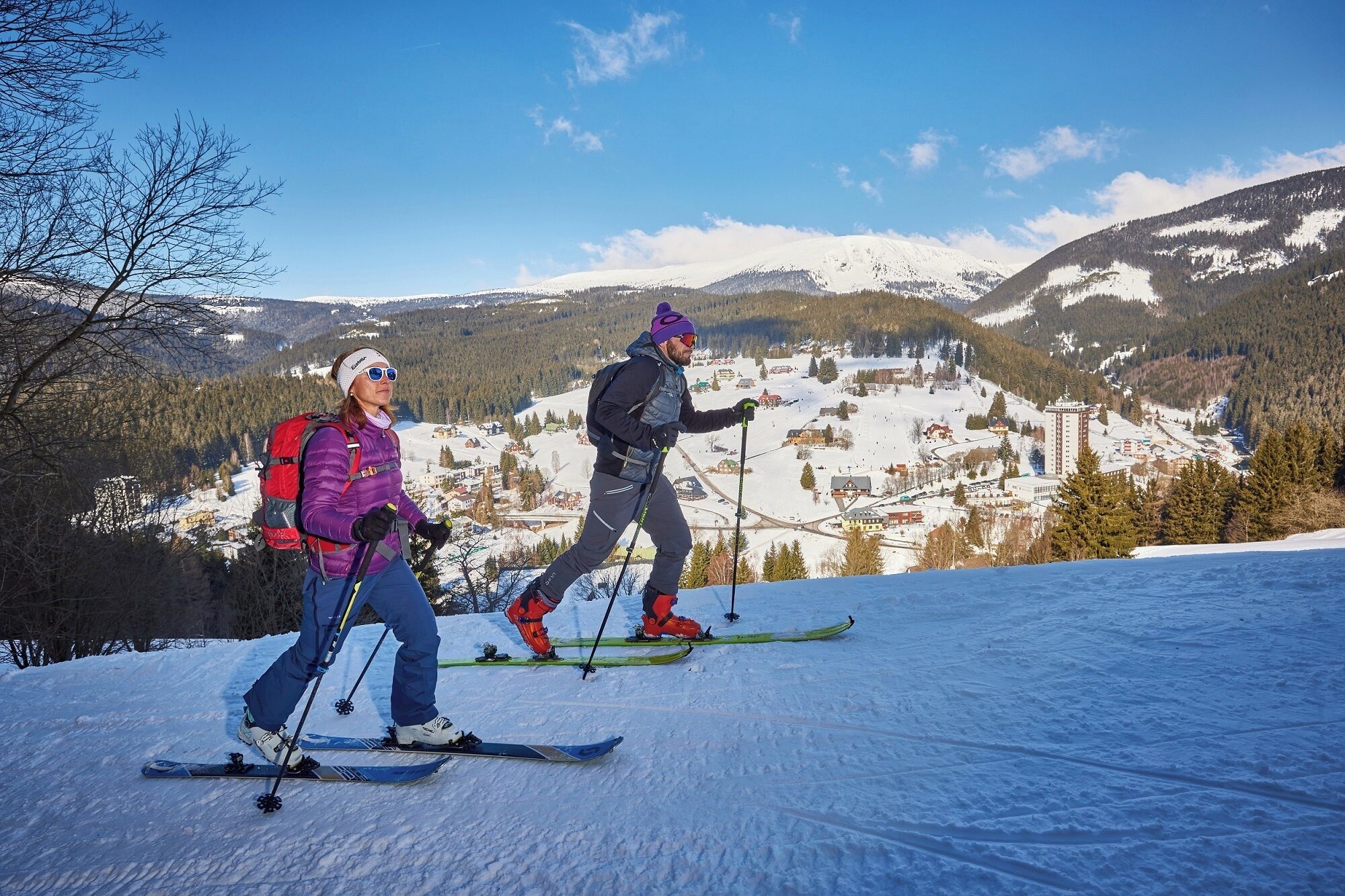 Two skiers on a snowy slope with a town in the background.
