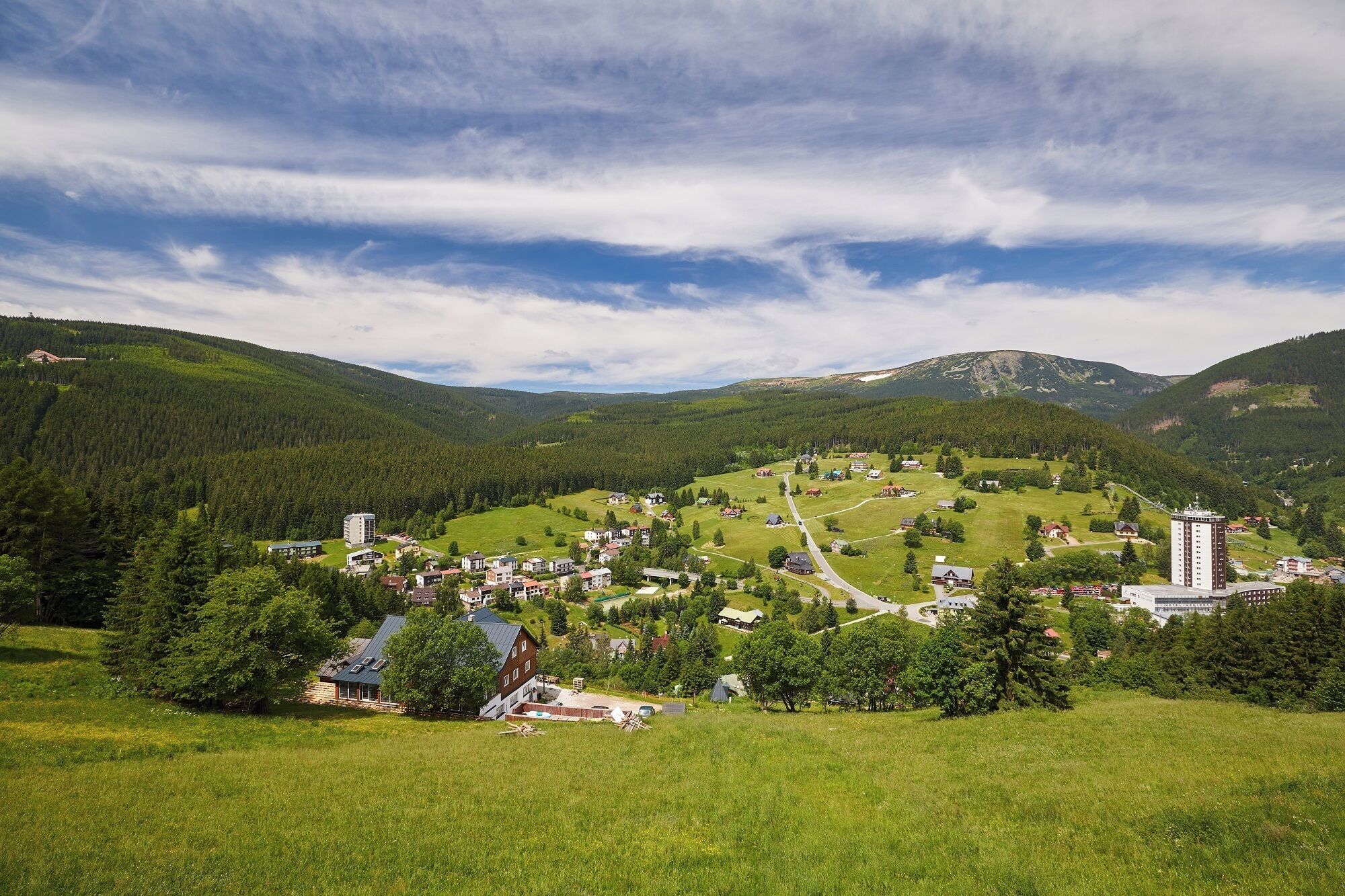 Un pueblo rural con una mezcla de viviendas y edificios comerciales, rodeado de abundante vegetación y montañas.