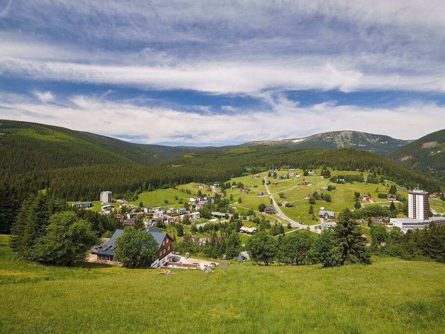 Un pueblo rural con una mezcla de viviendas y edificios comerciales, rodeado de abundante vegetación y montañas.