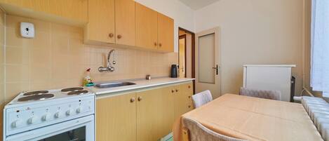 A compact kitchen with wooden cabinets, a white stove, and a sink.