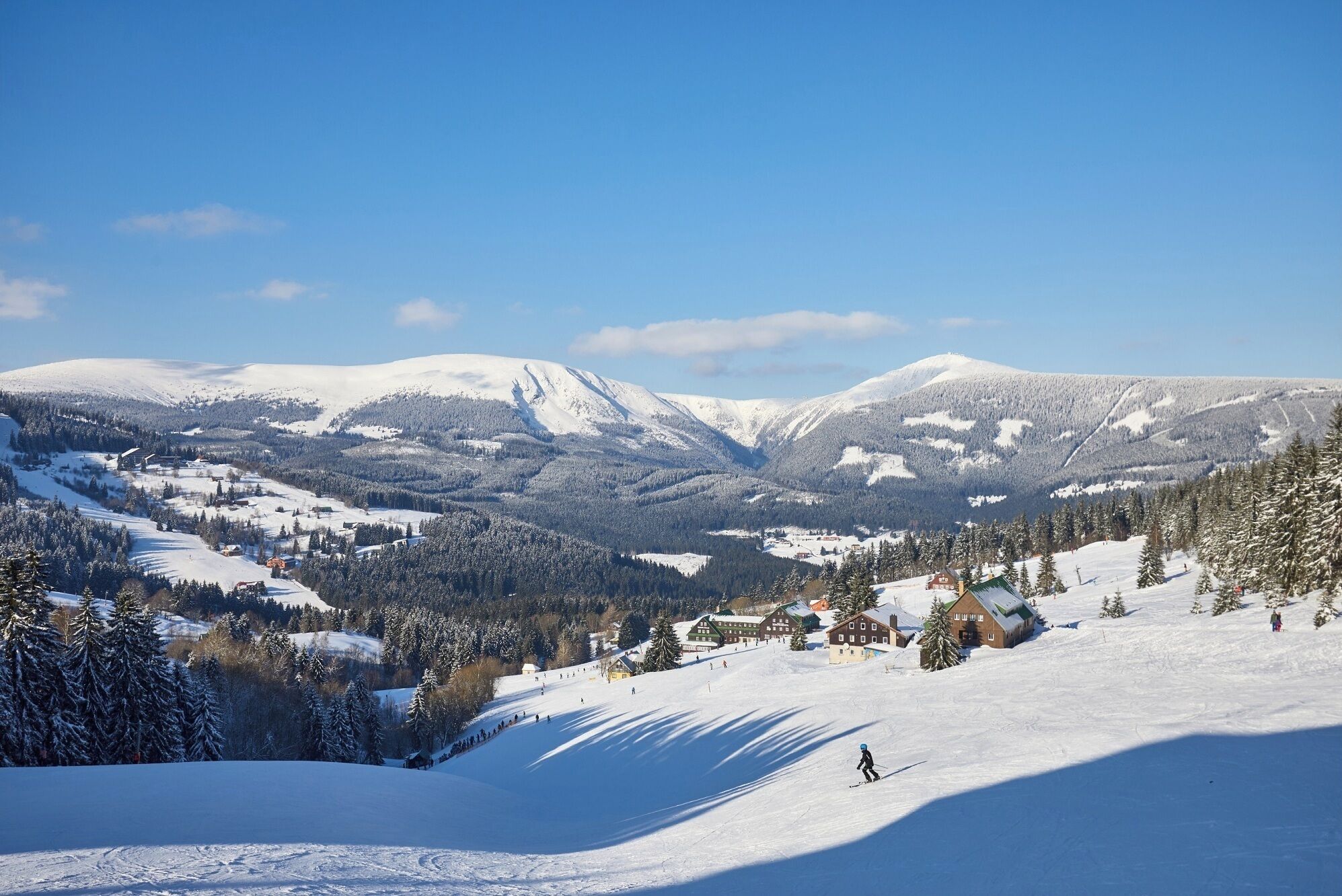 Un paysage montagneux enneigé avec une station de ski, comprenant des bâtiments et des pistes de ski.