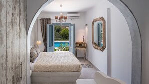 A bedroom with a bed, a desk, and a view of a pool. - Felicity Villas Santorini Luxury House (Santorini)