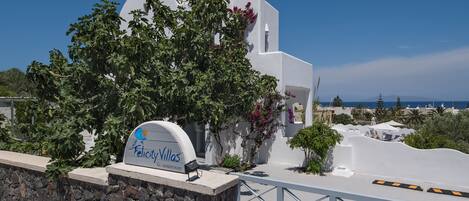 A white villa with a stone wall and a sign for 'Felicity Villas'.