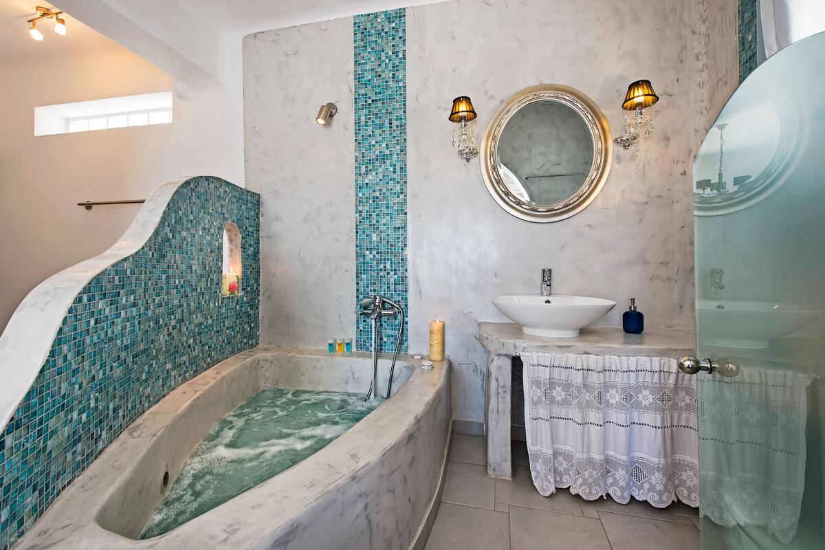 A bathroom with a large bathtub, a sink, and a mirror.