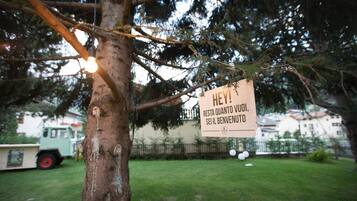 Un letrero en un árbol en una zona residencial, con césped y un vehículo estacionado al fondo.