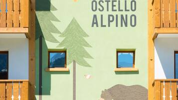 Ein Gebäude mit der Aufschrift "Ostello Alpino" und einer Bär-Grafik an der Fassade.