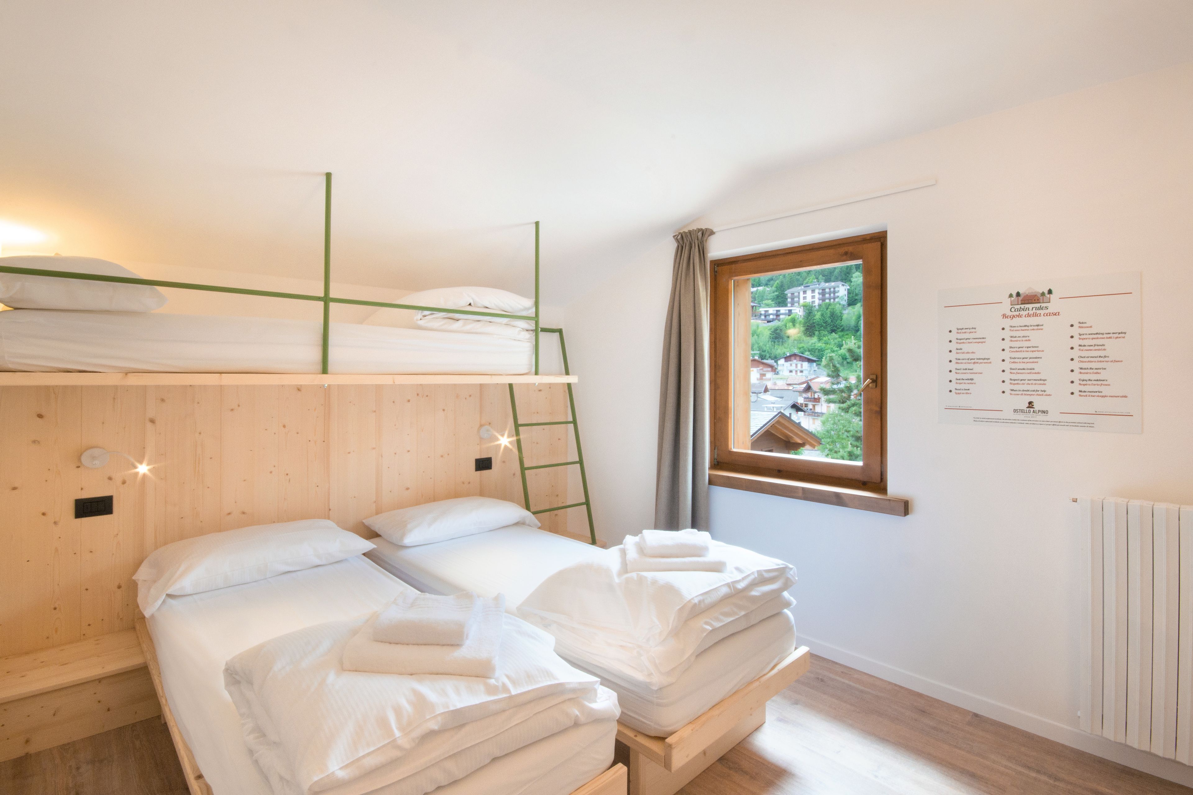 A room with bunk beds, a window with a view, and a menu on the wall.