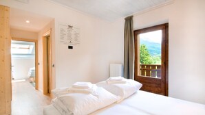 Une chambre d’hôtel avec un lit, une porte en bois et une vue sur les montagnes.