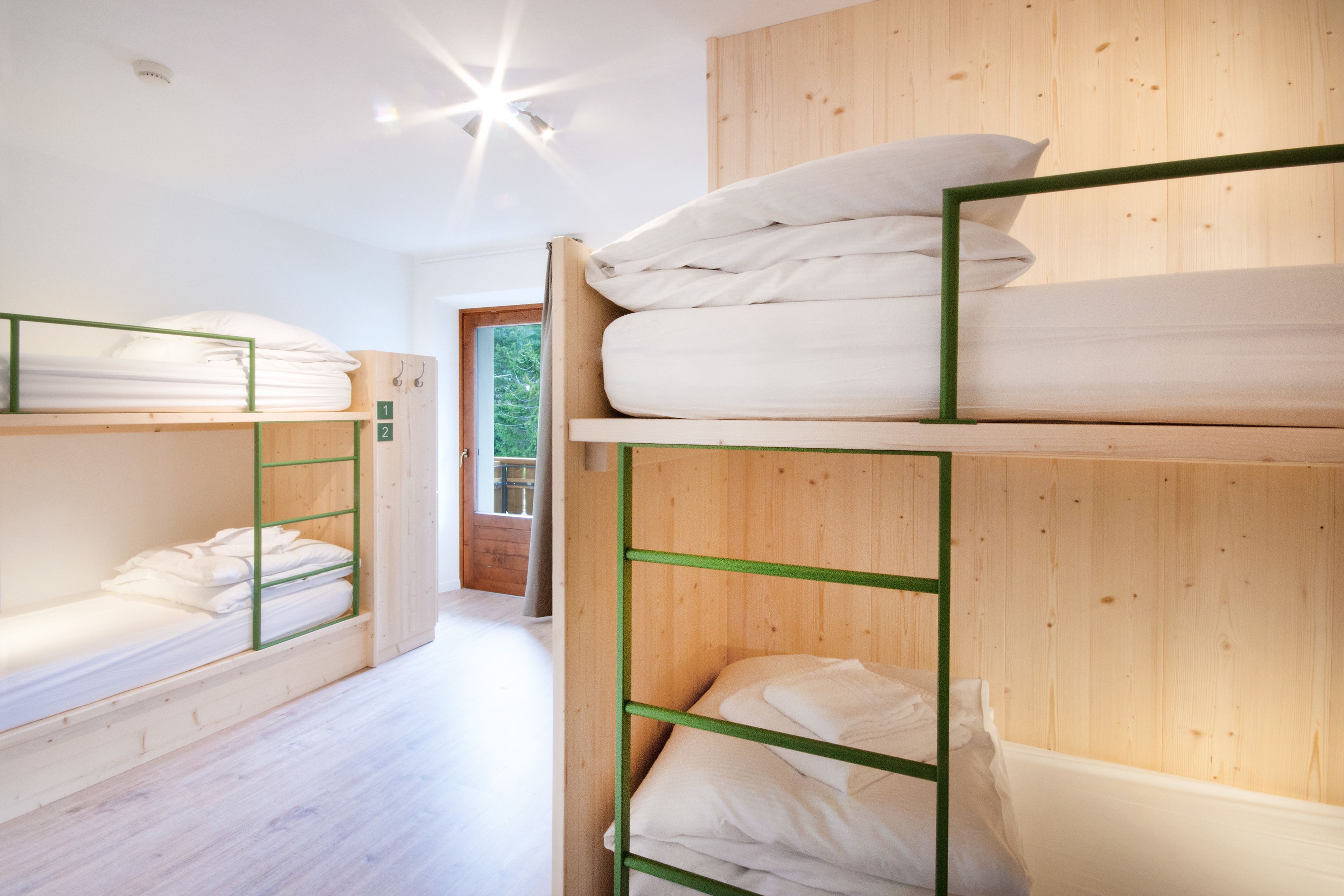 Dormitorio con literas, paredes y suelo de madera.