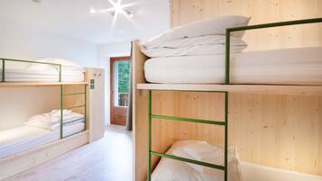 Dormitorio con literas, paredes y suelo de madera.