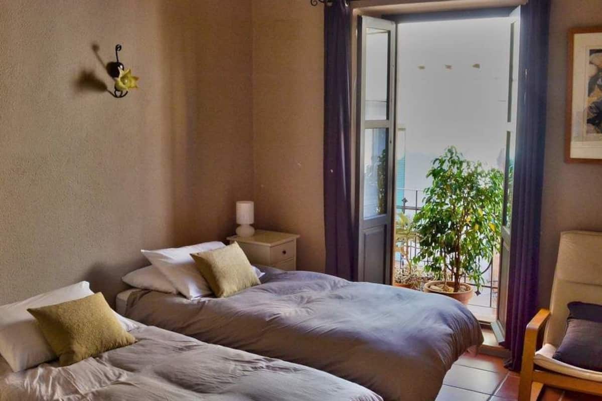 Un dormitorio con dos camas, una mesita de noche, una silla y una ventana con vistas al exterior.