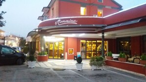A hotel entrance with a red facade, a sign reading "Mammina," and potted plants in front. - Hotel Residence Memmina (Frosinone)