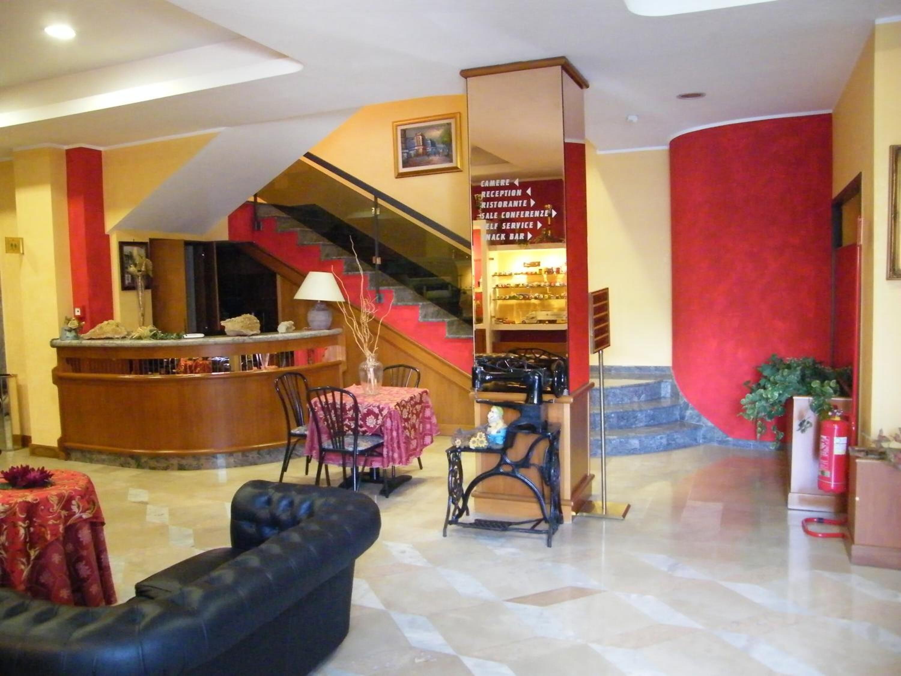 Eine Lobby mit einer Rezeption, einer Treppe, einer Bar und Sitzgelegenheiten.