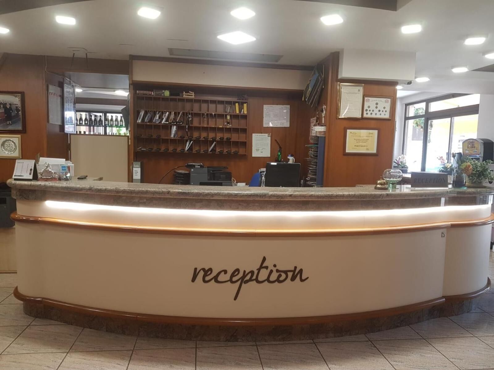 Un espace d’accueil avec un comptoir portant l’inscription « réception  », un intérieur en bois et une fenêtre en arrière-plan.