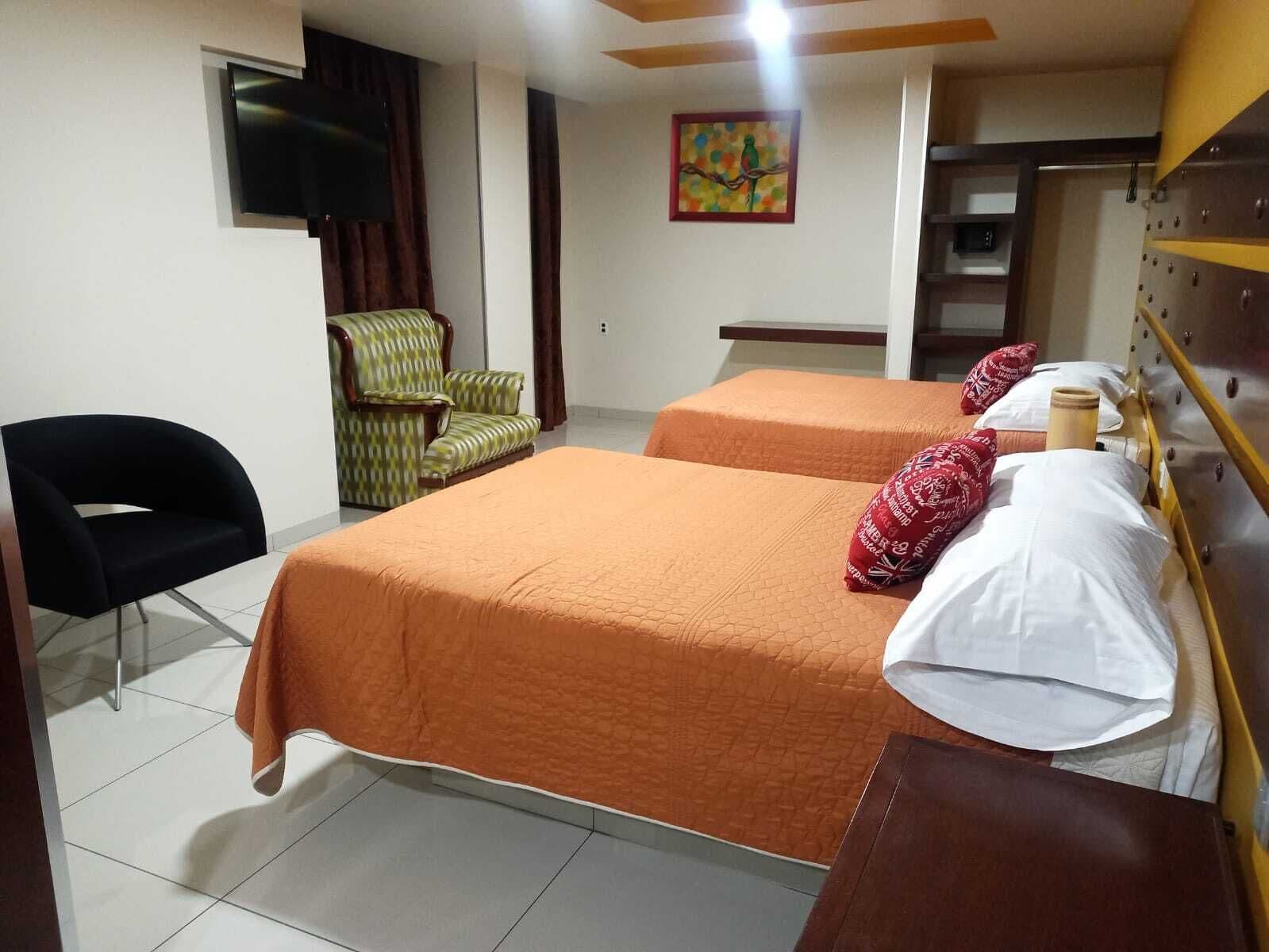 A hotel room with two beds, a TV, a chair, and a painting on the wall.
