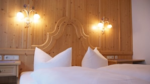 A hotel room with a wooden headboard, two bedside tables, and a bed with white bedding. - Sportapart Mallaun (See)