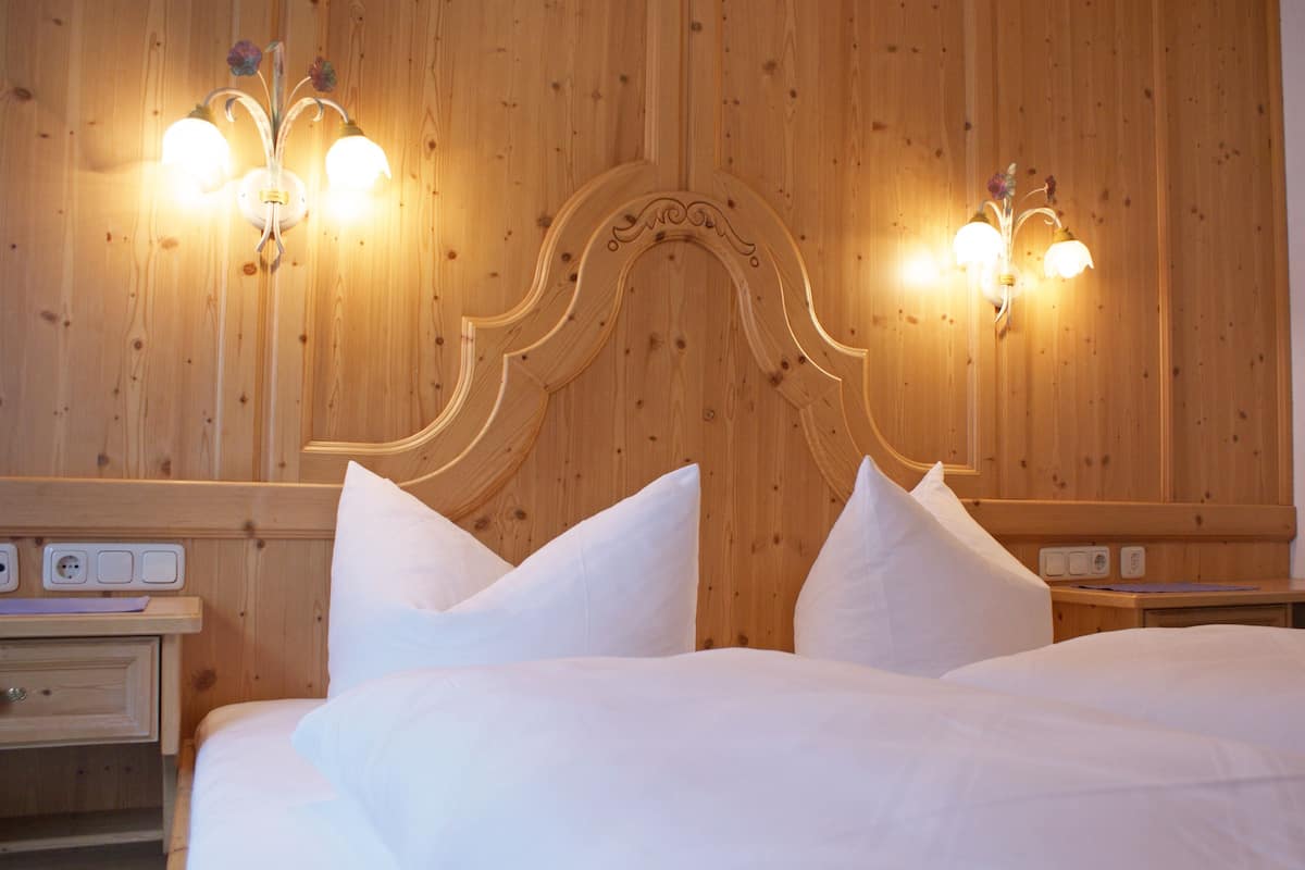 A hotel room with a wooden headboard, two bedside tables, and a bed with white bedding.