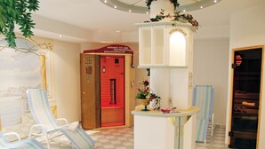 A hotel lobby with checkered flooring, striped lounge chairs, a reception desk with a vase of flowers, and a red door labeled 'VITAMINBAR'. - Sportapart Mallaun (See)