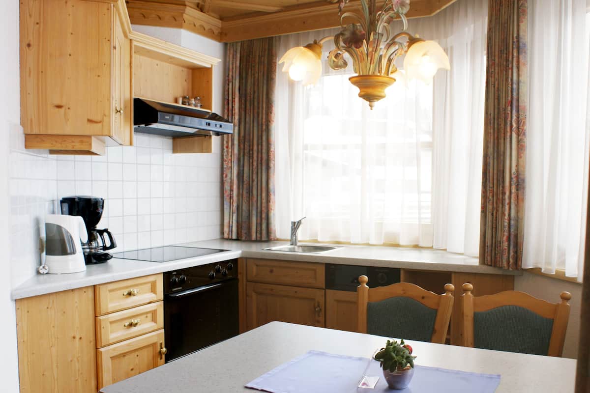 A kitchen with wooden cabinets, a stove, a sink, and a dining table with chairs.