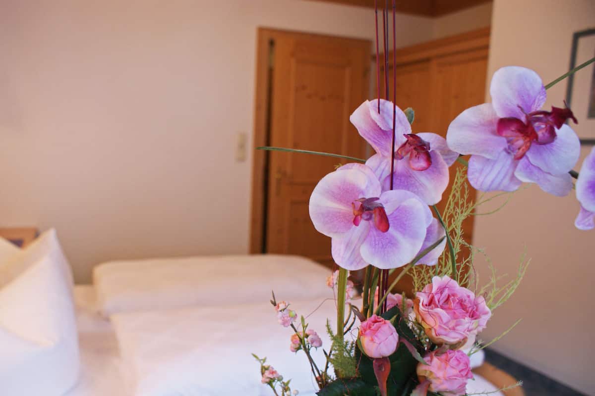 A hotel room with a bed, a bedside table, and a vase with flowers.