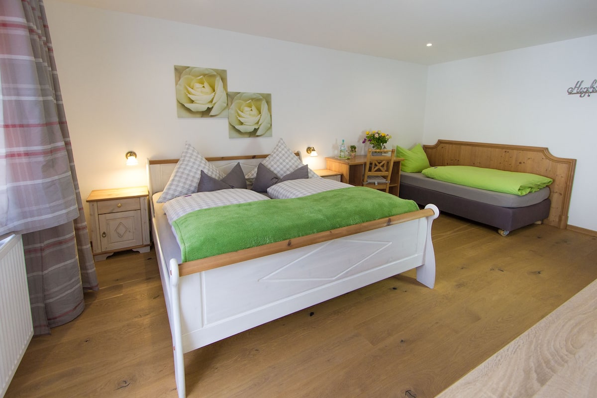 Un dormitorio con cama, mesita de noche, cómoda y una silla.