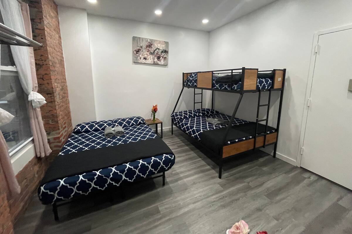 Una habitación con dos literas, una mesita con un jarrón y un cuadro en la pared.